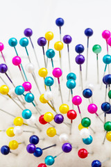 Multicolored sewing pins in the white pin cushion. Close-up