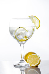 Glass of gin tonic with lemon on white background