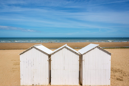 Three traditional white wooden beach huts on the beach of Villers, Normandy, France