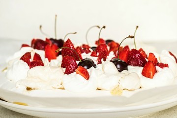 Cake Pavlova with strawberry and cherry on white.