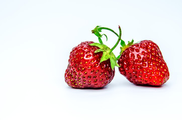 Two red whole ripe strawberries on white background.