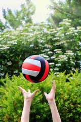volleyball fight off the hands of a teenager against the bright of blooming greenery and sunlight