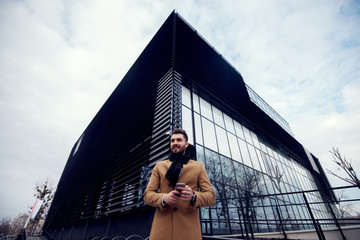 Fototapeta premium Attractive young man on the street, standing in front of the modern building.