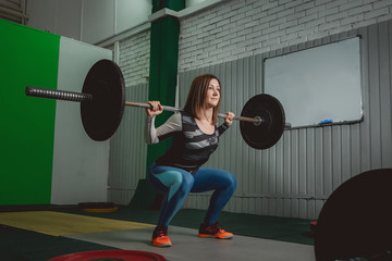 Naklejka na ściany i meble Strong woman lifting barbell as a part of crossfit exercise routine