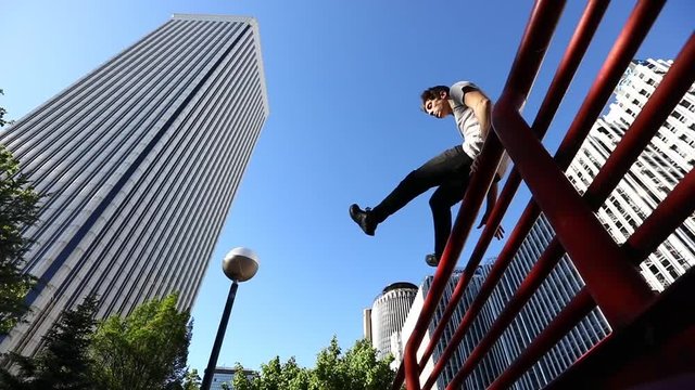 Man jumping over a fence in the city during a parkour session