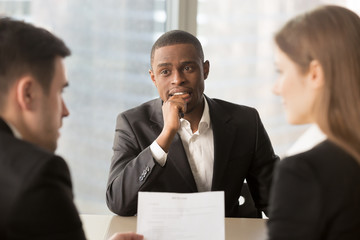Nervous worried unemployed african-american job applicant waiting for result while employers or...