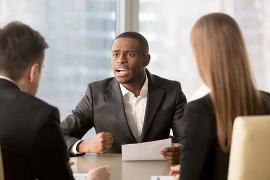 Dissatisfied african-american boss clenching fist, scolding employees for bad work, displeased team leader holding report arguing with subordinates, defrauded cheated investor demanding money back