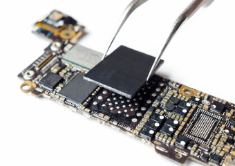 Close-up image of technician replacing flash storage (NAND) of smartphone motherboard