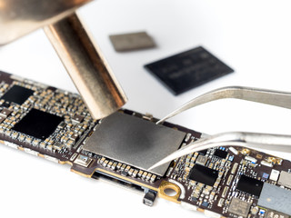 Close-up image of technician replacing flash storage (NAND) of smartphone motherboard