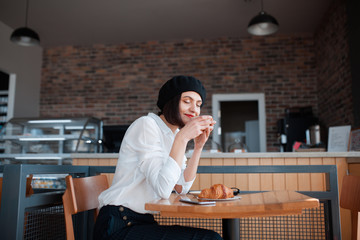 Woman in cafe enjoying coffee and croissant