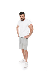 Portrait of confident muscular man posing in casual clothes and looking at camera isolated on white