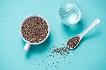 Glass of water with cup of healthy chia seeds and spoon. Text space.