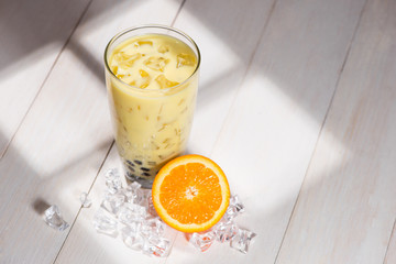 Bubble tea. Homemade Orange Milk Tea with Pearls on wooden table.