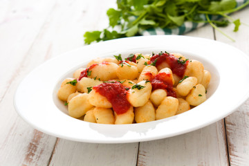 Gnocchi with tomato sauce on white wooden table
