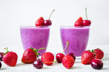 Smoothie of blueberry, cherry and strawberry and tasty summer berries on white wooden table. Fresh tasty milkshake