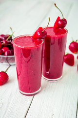 Cherry and strawberry smoothie and tasty berries on white table. Fresh natural milkshake