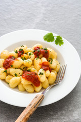 Gnocchi with tomato sauce on gray stone
