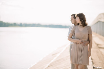 beautiful couple man and woman in a light beige light clothing spend time together, enjoying each other, talking,cuddling standing on the river Bank, a happy family, a love story