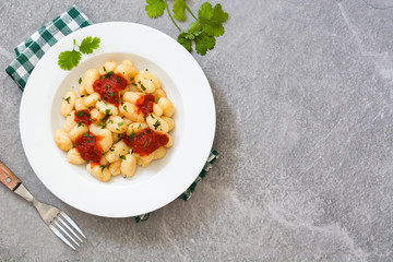Gnocchi with tomato sauce on gray stone
