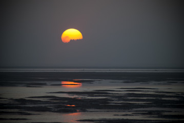 Sun rising over the ocean, partially covered