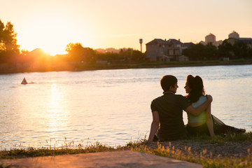 couple sitting on the river bank at sunset