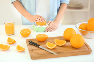 Obraz na płótnie Canvas Female hands making orange juice on kitchen