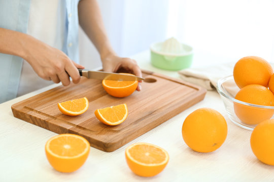 Female hands cutting orange on kitchen