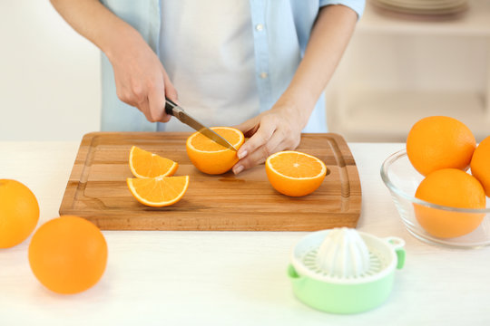 Female hands cutting orange on kitchen