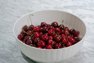 Ripe cherries in a white plastic bowl