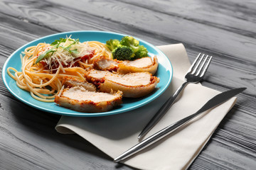 Tasty pasta with chicken parmesan slices and herbs on plate