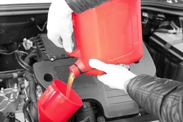 Male hands pouring engine oil from canister, closeup