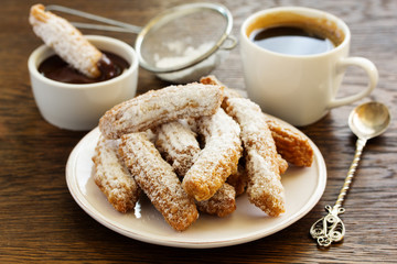 Churros with hot chocolate and powdered sugar.