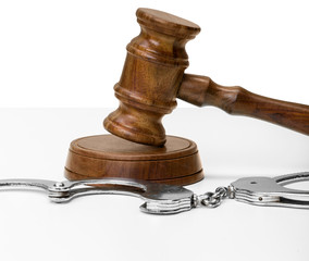 Gavel and handcuffs on wooden table background