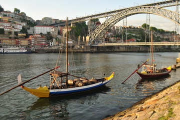 Barcos rabelos amarelo e azul parado no dio d'ouro no cais de Vila Nova de Gaia com a ponte Dom...