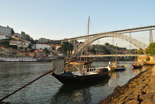 Dois Barcos Rabelos parados no cais de Vila Nova de Gaia ao final da tarde com ponte Dom Lu&iacute;s por tr&aacute;s