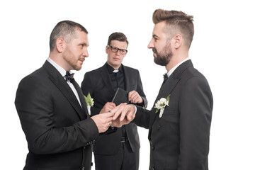 homosexual couple of grooms exchanging rings at wedding ceremony isolated on white