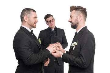smiling homosexual couple exchanging rings at wedding ceremony isolated on white