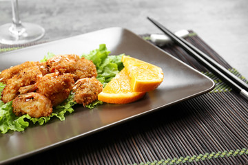 Plate with delicious coconut shrimps on table