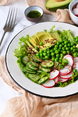 Mix salad with cucumber, avocado, green peas and flax seeds on a marble background