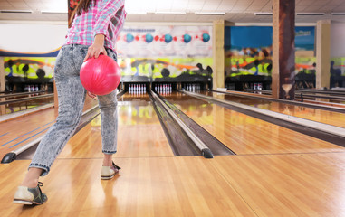 Young woman with ball in bowling club