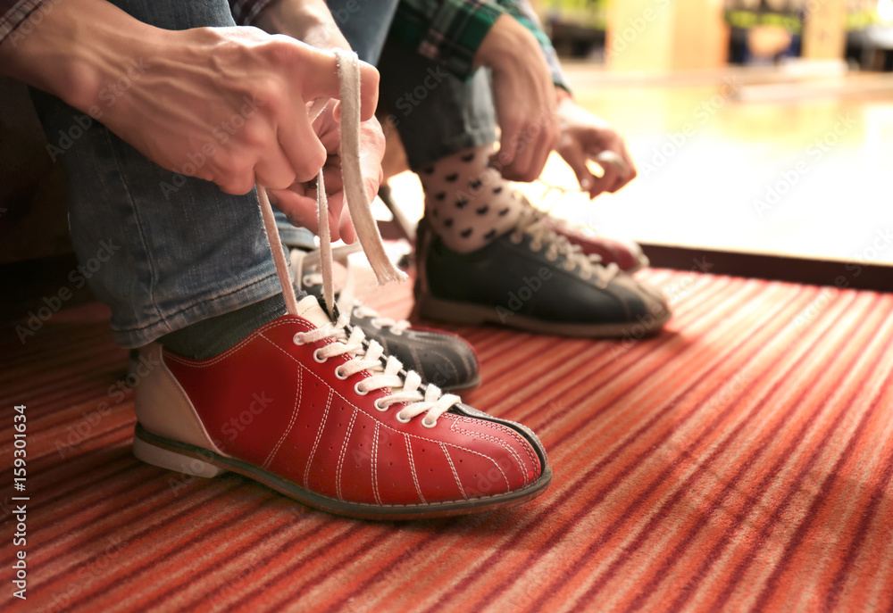 Poster Friends lacing their shoes in bowling club