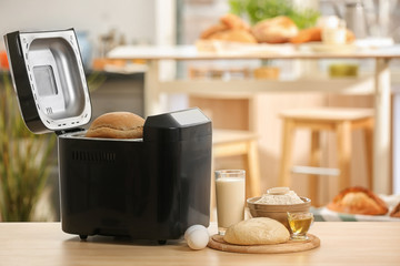 Tasty loaf in bread machine and dough on table