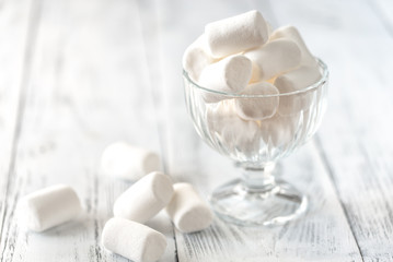Fototapeta na wymiar Glass bowl of marshmallows on the wooden background