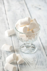 Glass bowl of marshmallows on the wooden background