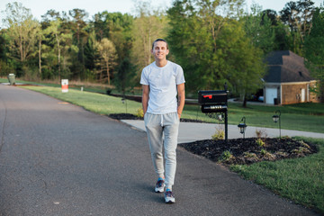 Relaxed and calm american young man in his twenties, takes an evening walk to his grandparents house to pay a visit, wearing his casual comfy clothes on warm summer evening