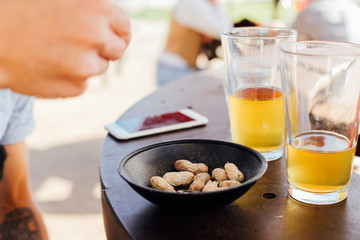 Dirty table with american typical snack roasted peanuts and two pints of artisan craft beer