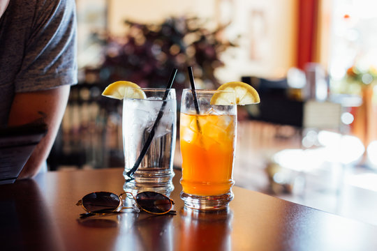 Refreshing Glass Of Ice Cold Water With Cubes, And Ice-tea Arnold Palmer Drink With Tea And Lemonade Mixed For Hot Summer Day Refreshements With Straws