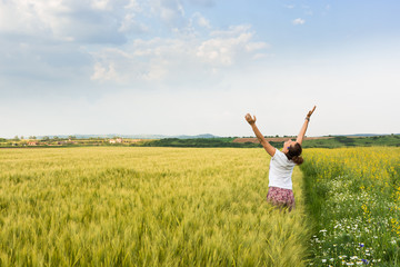 Adult woman enjoys the crop of wheat and rapeseed