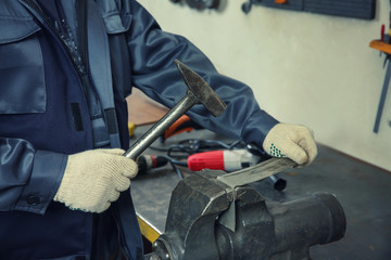 Man using grip and hammer for metalworking in shop
