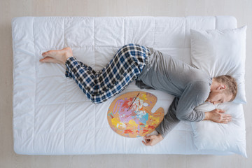 Creative nice man sleeping with an artist palette